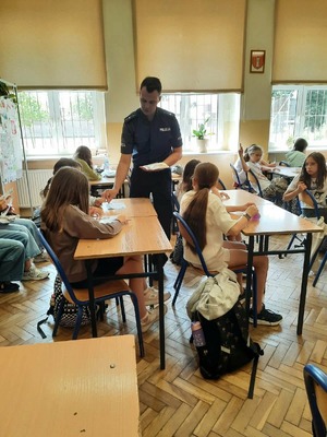Policjant rozdaje ulotki dzieciom w klasie.