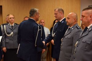 Sala odpraw wieluńskiej jednostki Policji. Zastępca Komendanta Wojewódzkiego Policji w Łodzi wraz z  Komendantem Powiatowym Policji w Wieluniu wręczają policjantom akty mianowania na wyższe stopnie policyjne.