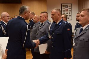 Sala odpraw wieluńskiej jednostki Policji. Zastępca Komendanta Wojewódzkiego Policji w Łodzi wraz z  Komendantem Powiatowym Policji w Wieluniu wręczają policjantom akty mianowania na wyższe stopnie policyjne.