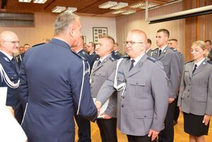 Sala odpraw wieluńskiej jednostki Policji. Zastępca Komendanta Wojewódzkiego Policji w Łodzi wraz z  Komendantem Powiatowym Policji w Wieluniu wręczają policjantom akty mianowania na wyższe stopnie policyjne.