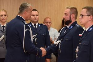Sala odpraw wieluńskiej jednostki Policji. Zastępca Komendanta Wojewódzkiego Policji w Łodzi wraz z  Komendantem Powiatowym Policji w Wieluniu wręczają policjantom akty mianowania na wyższe stopnie policyjne.