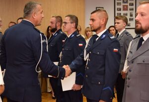 Sala odpraw wieluńskiej jednostki Policji. Zastępca Komendanta Wojewódzkiego Policji w Łodzi wraz z  Komendantem Powiatowym Policji w Wieluniu wręczają policjantom akty mianowania na wyższe stopnie policyjne.