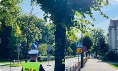 Policjant stoi przy drodze do szkoły.