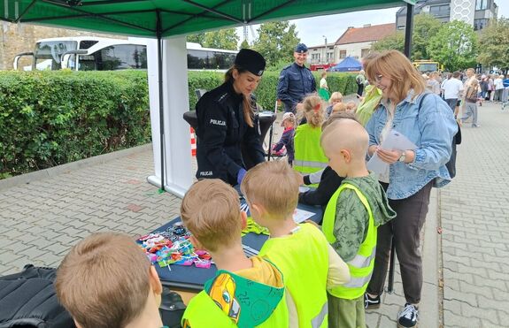 Policjantka na stoisku profilaktycznym rozmawia z dziećmi.
