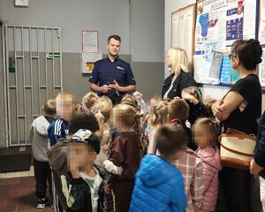 Korytarz w komendzie policji w Wieluniu, policjant rozmawia z przedszkolakami.