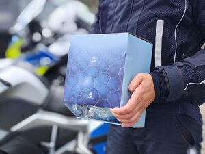 Policjant w ręku trzyma pudełko w którym zapakowany jest kas ochronny.