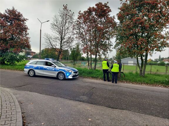 Dwoje policjantów kamizelkach odblaskowych wraz z rowerzysta